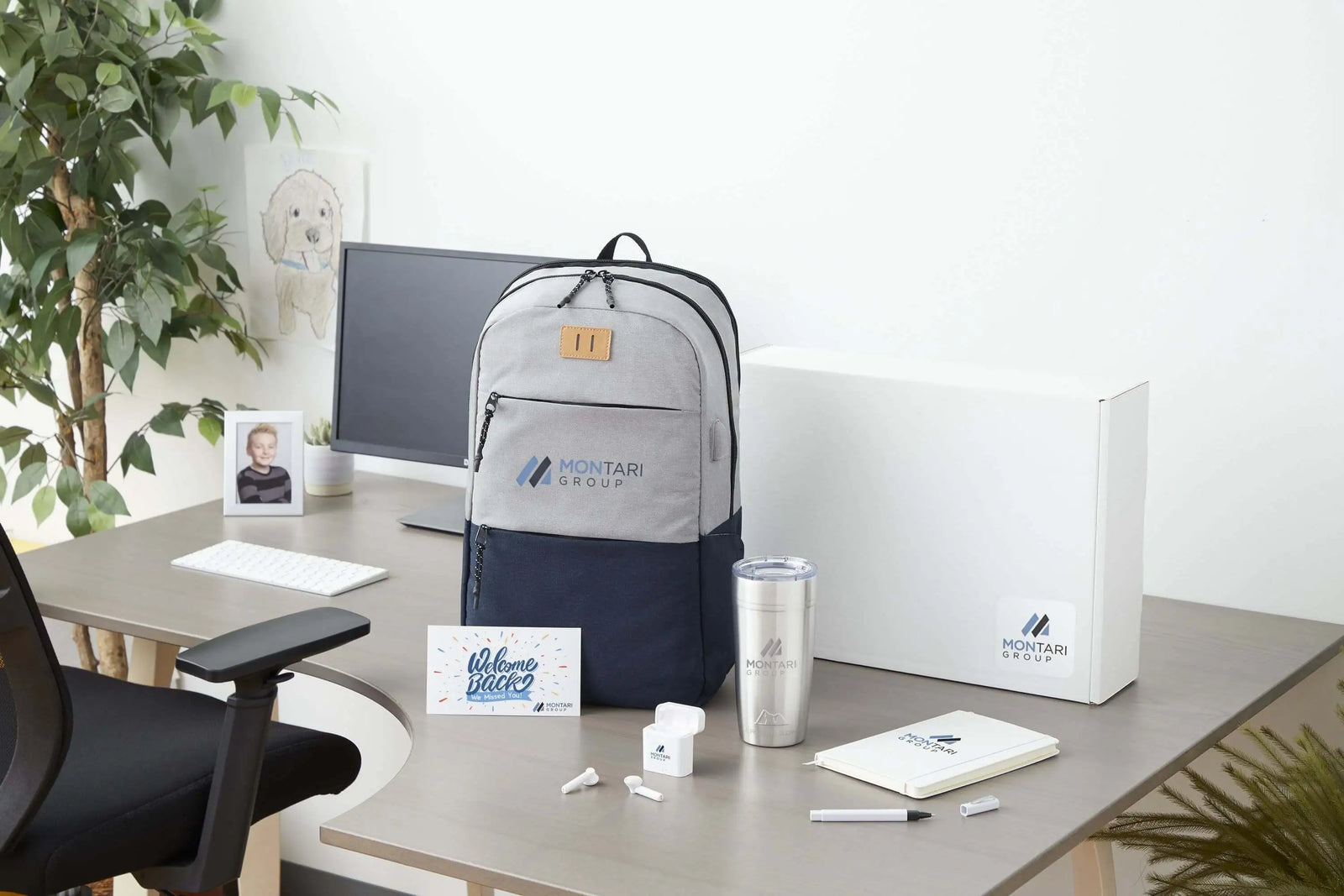A new hire onboarding kit featuring a branded backpack, stainless steel tumbler, wireless earbuds, notebook, pen, and welcome card.