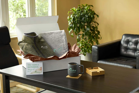 New employee welcome kit featuring a branded fleece, blanket, ceramic mug, coaster, and welcome card.