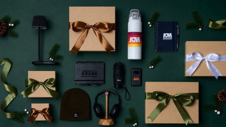 Corporate holiday gift boxes with branded drinkware, notebooks, headphones, and accessories.